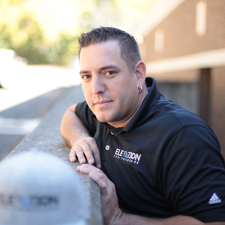 portrait of Adam Uzzo, print shop manager at marketing agency Elevation Ten Thousand wearing branded collared shirt