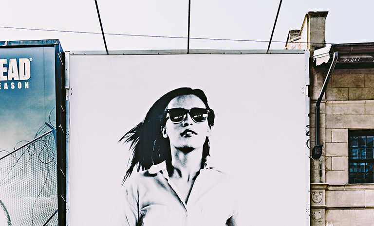 closeup of an exterior wall between two buildings that features a black and white photo of a woman wearing sunglasses