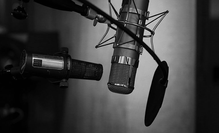radio and recording equipment in black and white, including microphones and a pop filter