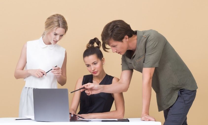 Two women and a man looking at a laptop critiquing the work