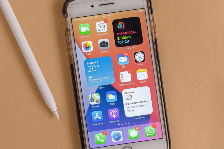 white Apple iPhone with coordinating stylus and earbuds on a desk in front of a black keyboard