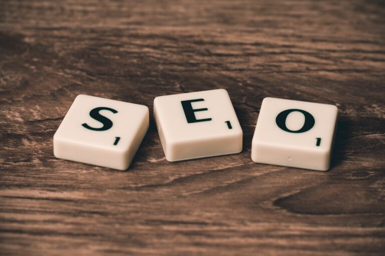 three white tiles with black capitalized letters that spell “SEO” lying on dark brown wooden surface
