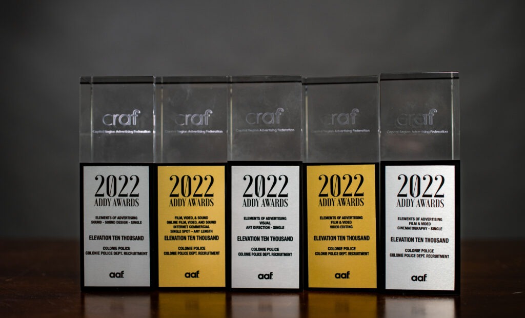 five Capital Region Advertising ADDY Awards for content marketing with silver and gold plaques lined up on a wooden table