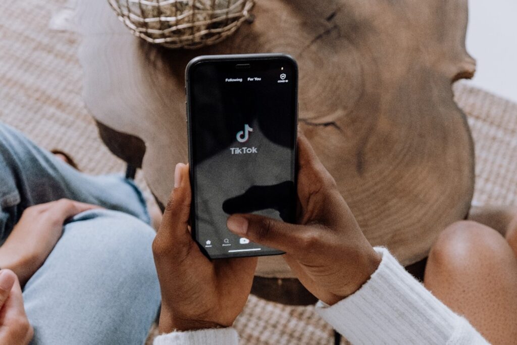 Adult holding a black iPhone phone with the TikTok app opened