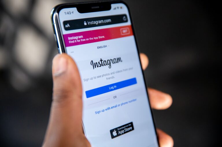 adult hand holding a black cell phone with the Instagram login screen open