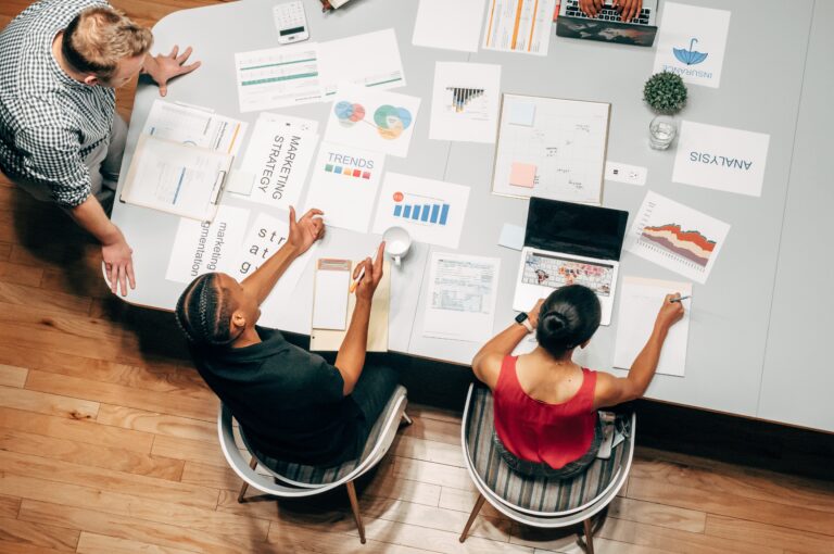 overhead shot of adults at a conference table looking at sheets of paper showing a marketing strategy
