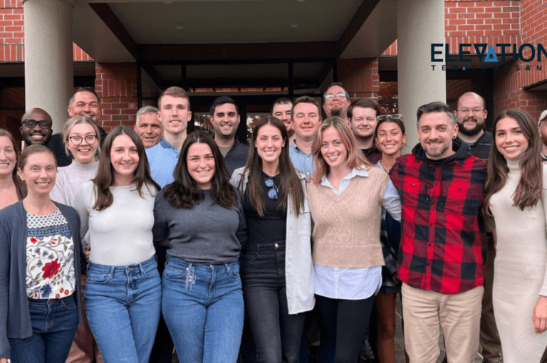 group of adults standing in front of a brick building after winning a Best Place to Work Award for 2022
