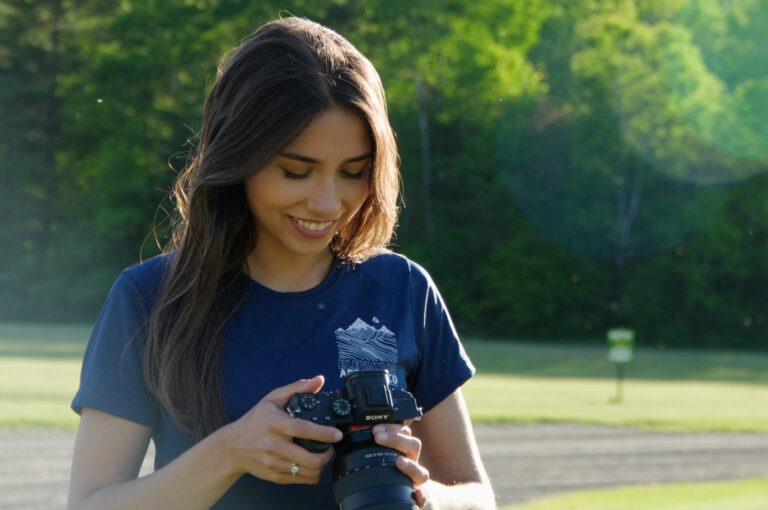 Woman wearing T-shirt standing outside looking at a photo taken on her camera