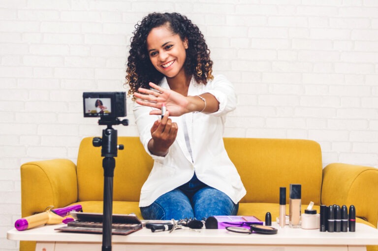 Young social media influencer vlogging about makeup sitting on a yellow couch