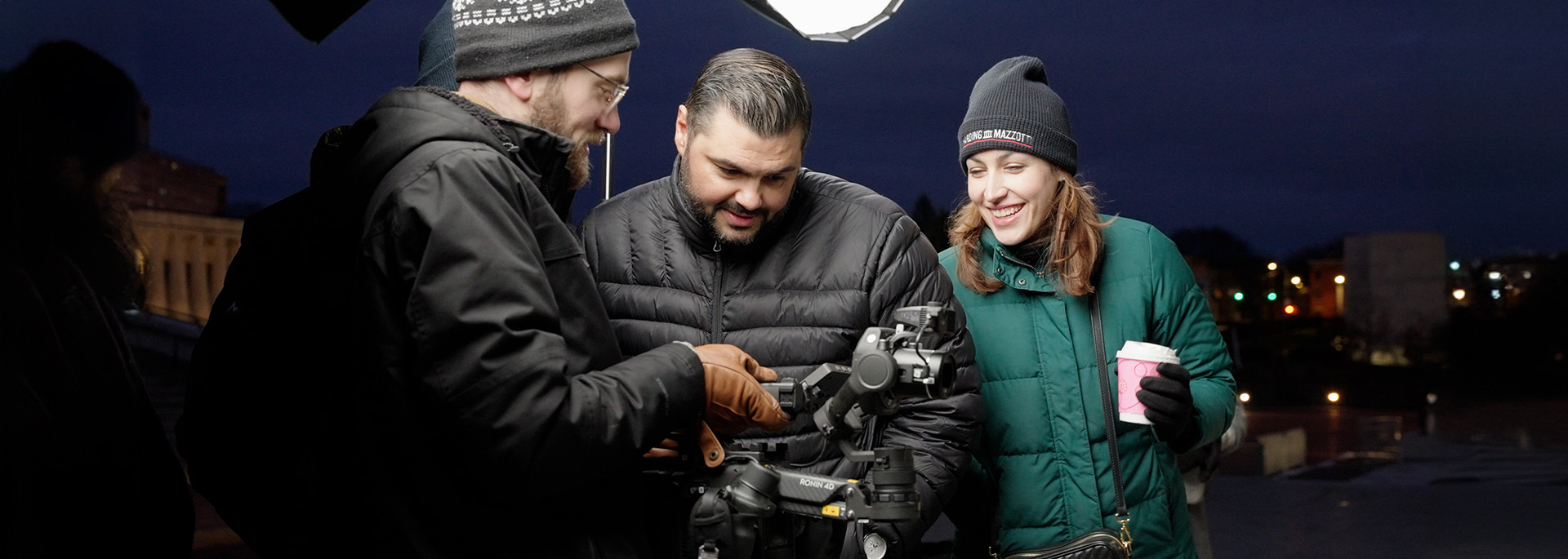 Three people looking at a video camera on the set of a shoot