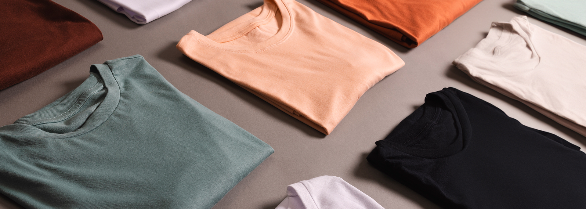 several colored tshirts laid out on a gray surface